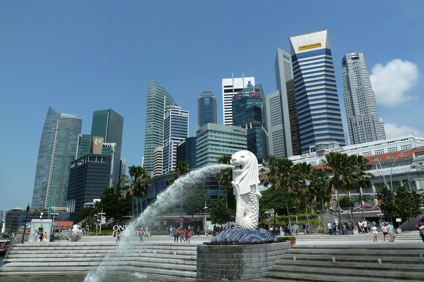 A statue fountain spits water in a harbour.