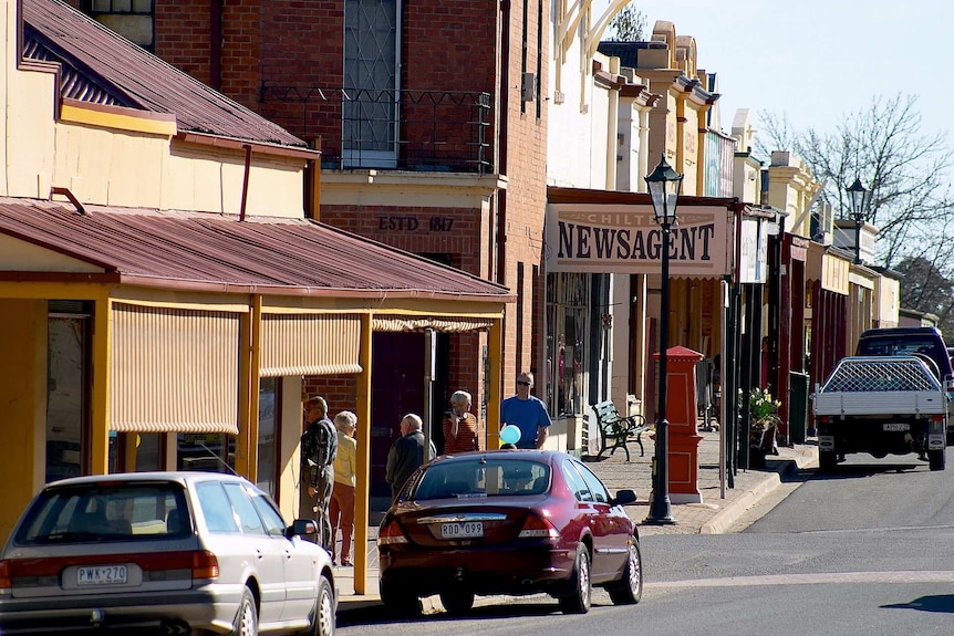 a street of a regional town down with shops, people and cars