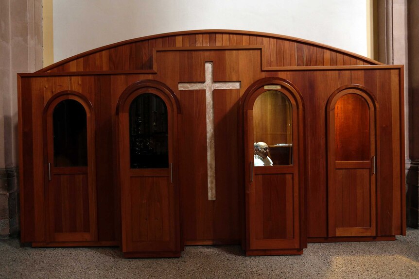 A priest sits in a confessional.