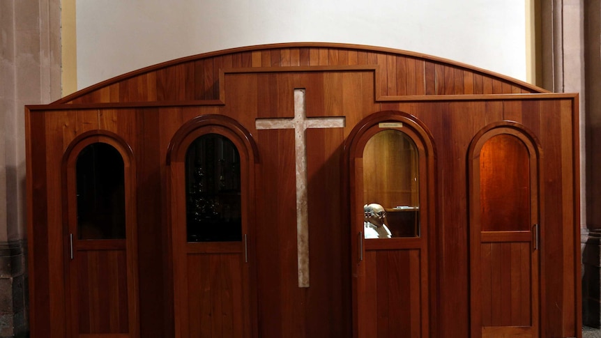 A priest sits in a confessional.