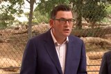 Daniel Andrews speaks in front of a lion enclosure at a zoo