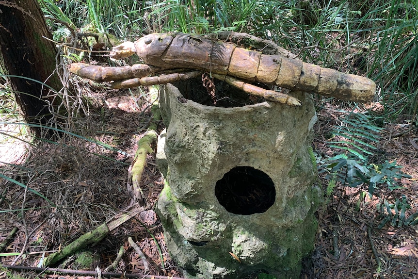Una instalación de arte con un cangrejo de río y un tocón en el bosque.