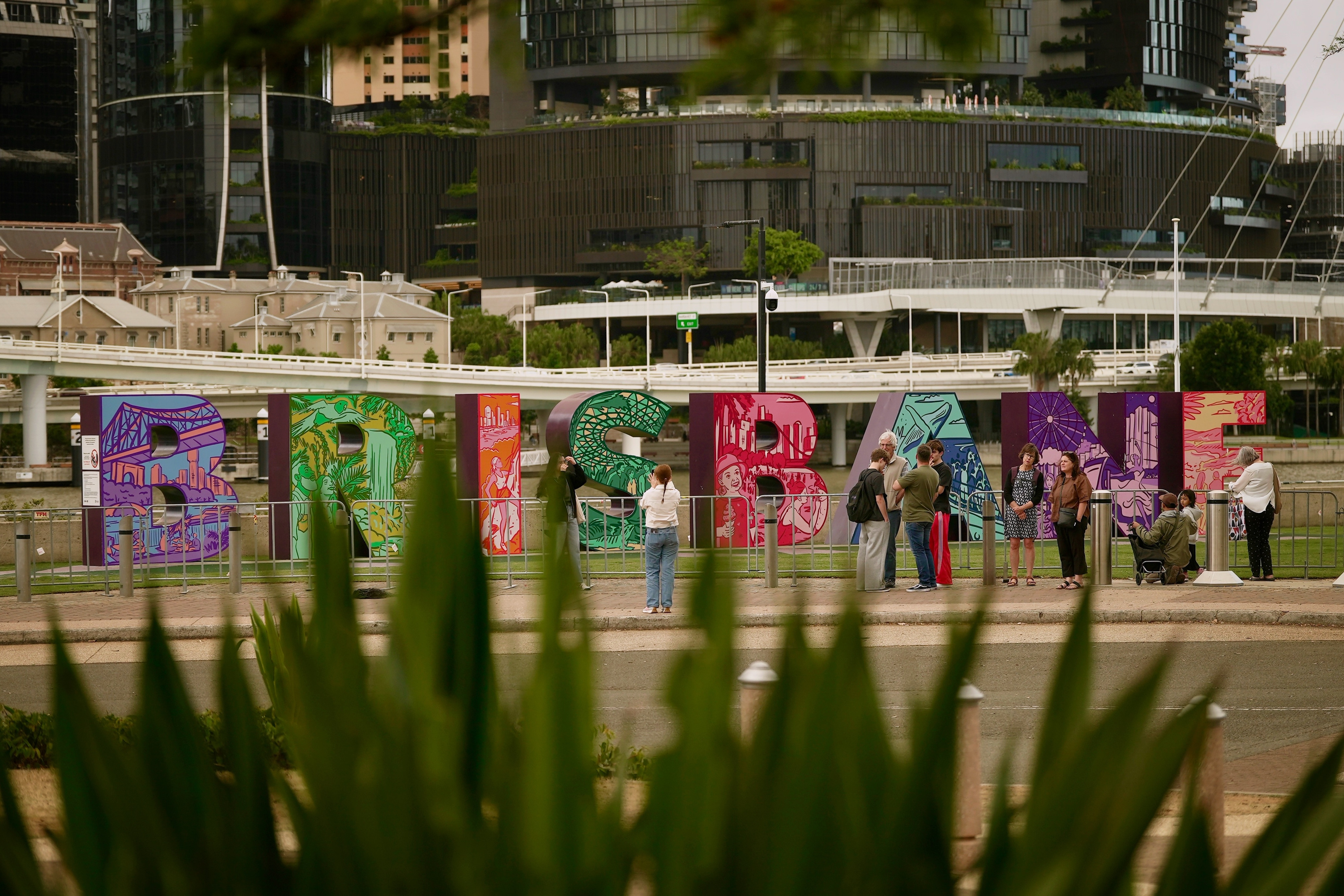 people looking at a big brisbane sign
