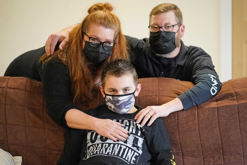 Cooper Wuthrich sits on a couch in front of his mother Dani and father Kale.
