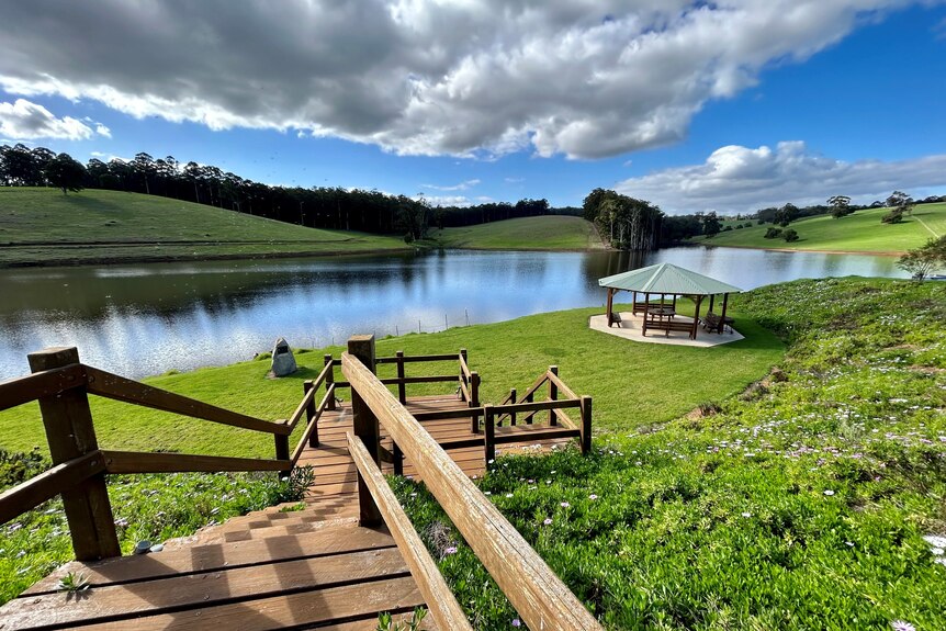 A staircase leads down to a lake surrounded by green hills. 
