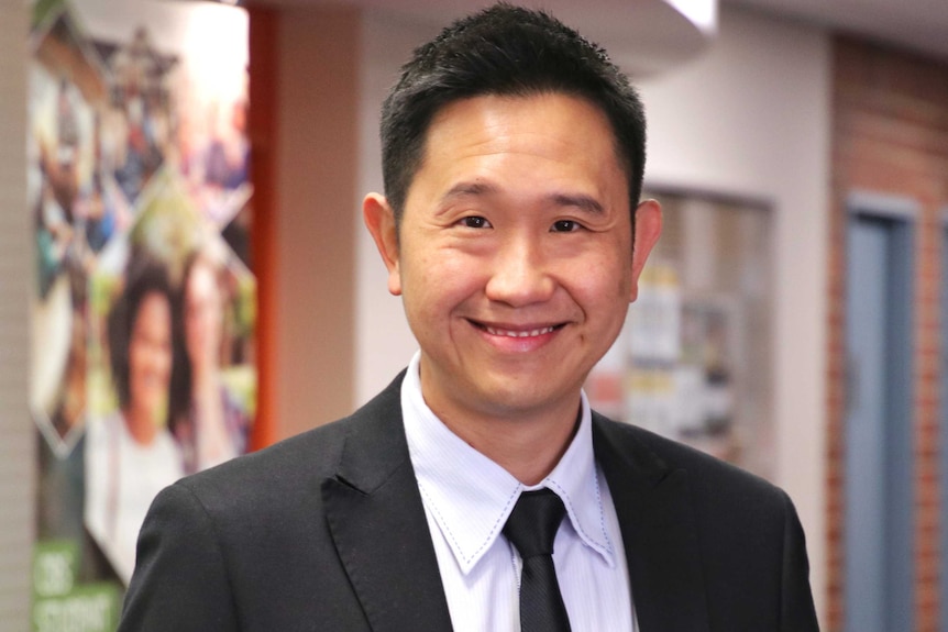 A medium close up of Elson Gob in a black suit with a white shirt.