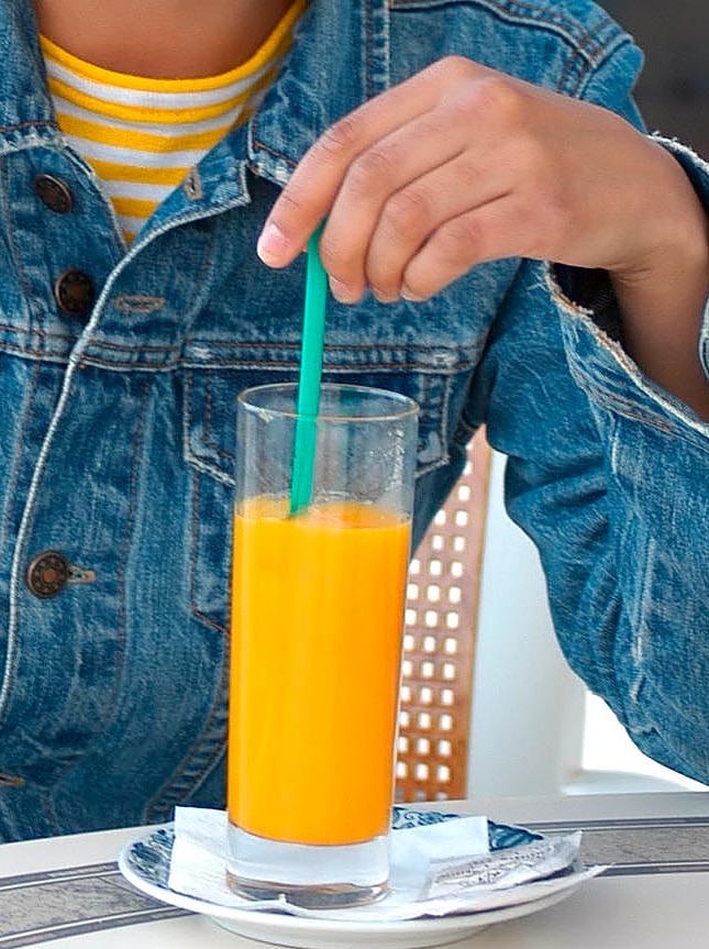 Young person drinking glass of orange juice.