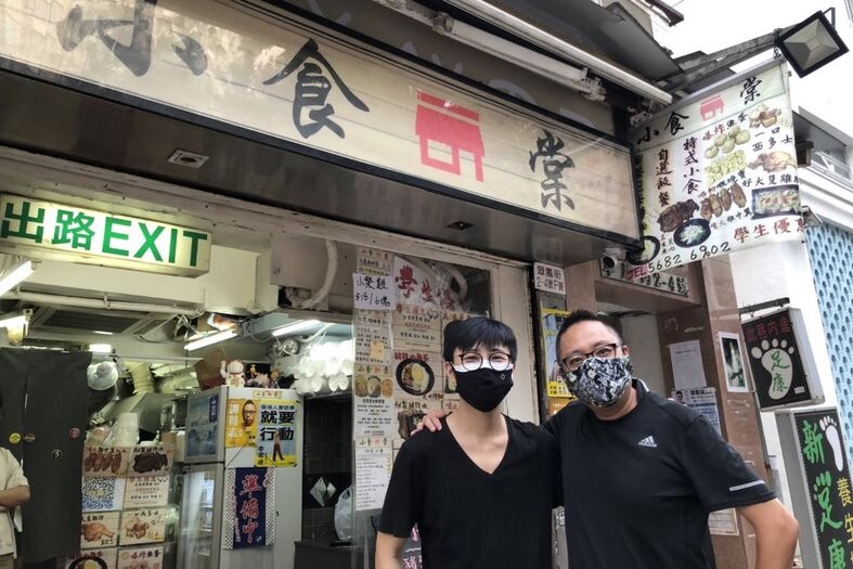 Mr Leung standing in the front of his shop with a friend 