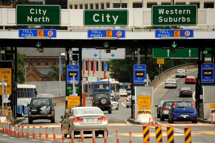 Cars on a road leading into Sydney, with toll signs above saying city north, city and western suburbs.