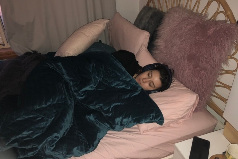 a woman lies in a bed covered by a doona