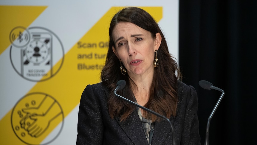 Jacinda Ardern behind a lectern speaking at a press conference. 