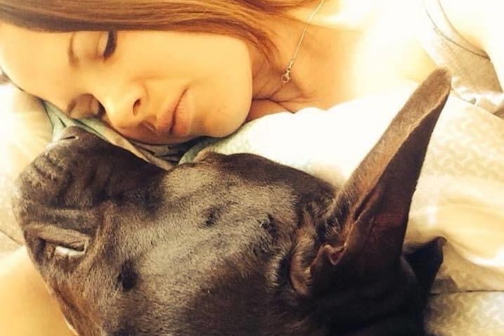 A close up image of a large dog cuddling with a young woman.