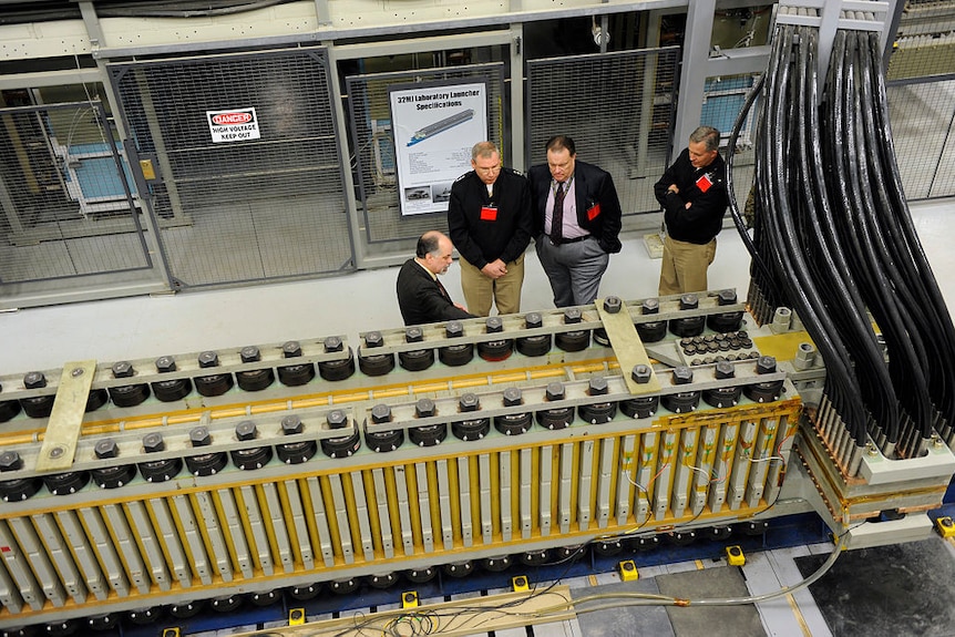 A large series of cylindrical power conductors in bright yellow are hooked to multiple groupings of thick black wires.