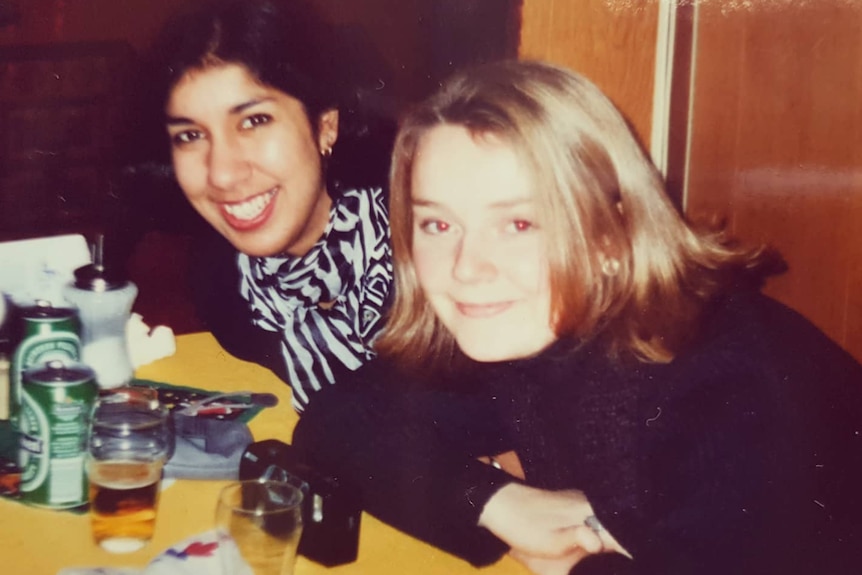 A young blonde woman and a young dark-haired woman pose for a photo.