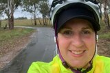 Giulia Jones in a fluro vest rides a bike in the rain.