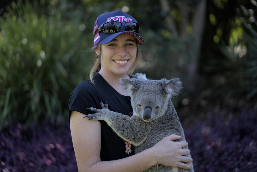 Teenage girl holds a koala at Australia Zoo