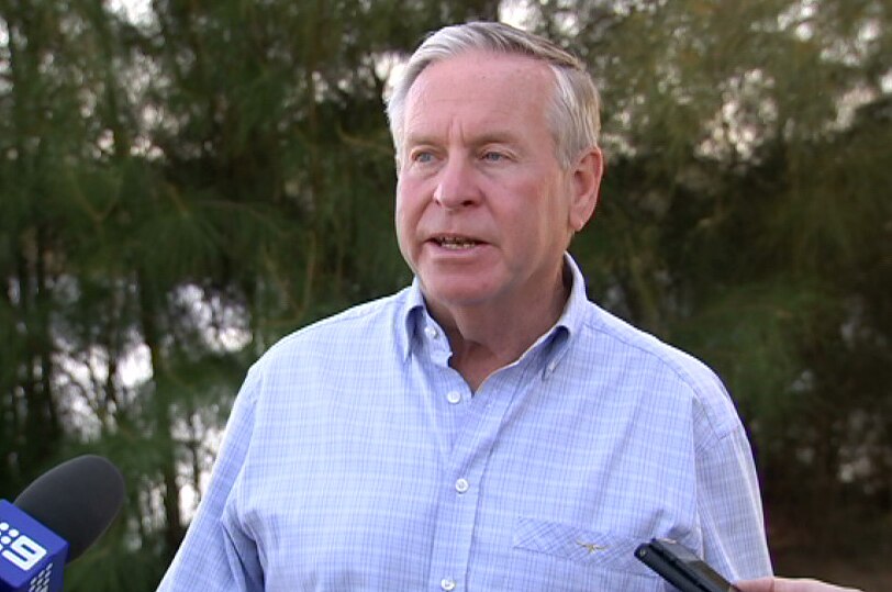 A mid-shot of Colin Barnett speaking to reporters wearing a white and blue shirt.