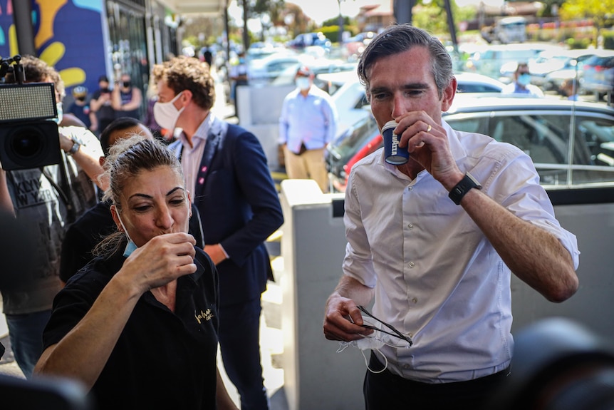 dominic perrottet drinking coffee with a barista surrounded by cameras