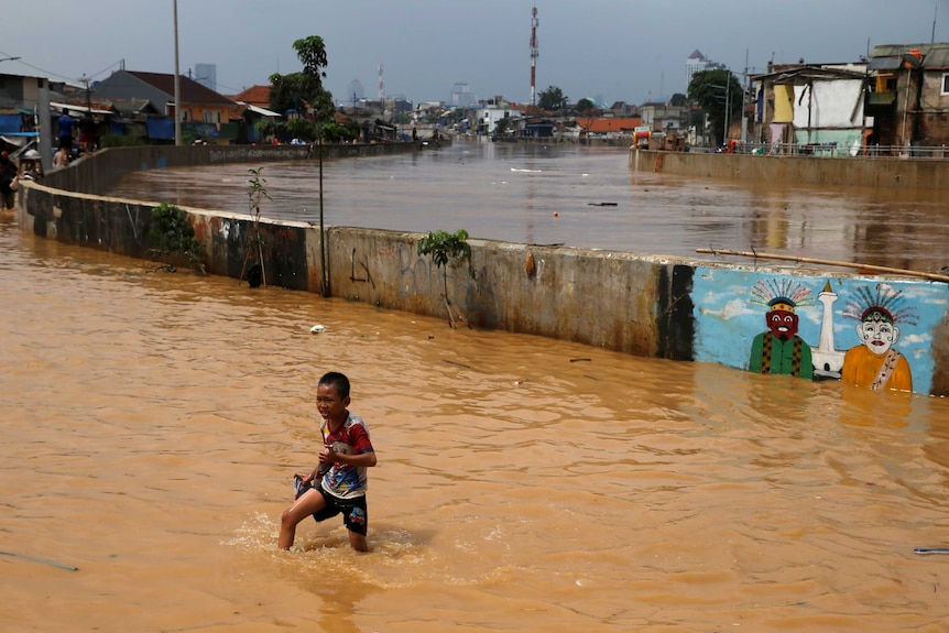 A child wades through a flooded street in Jatinegara district in Jakarta