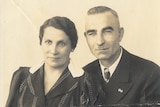 Grainy black and white photo of a man and woman standing, while the man holds the woman, and both smile.