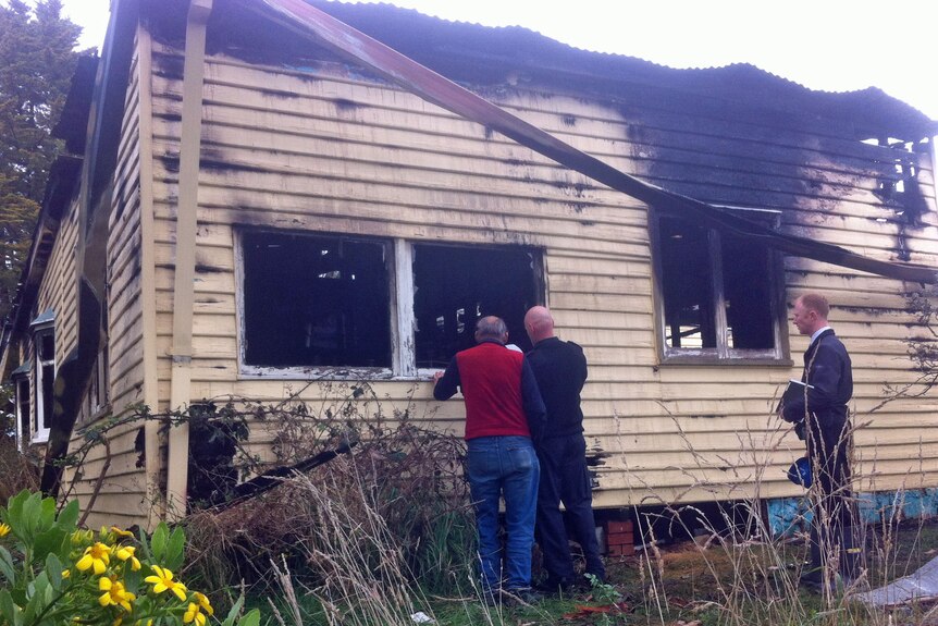 The owner and firemen inspect a Risdon Vale home destroyed by fire