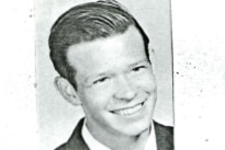 A young white man in a smiling headshot scanned in black and white
