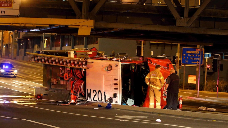A fire truck lies on its side after rolling over while on its way to a fire.