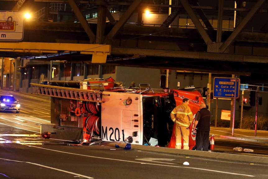 A fire truck lies on its side after rolling over while on its way to a fire.