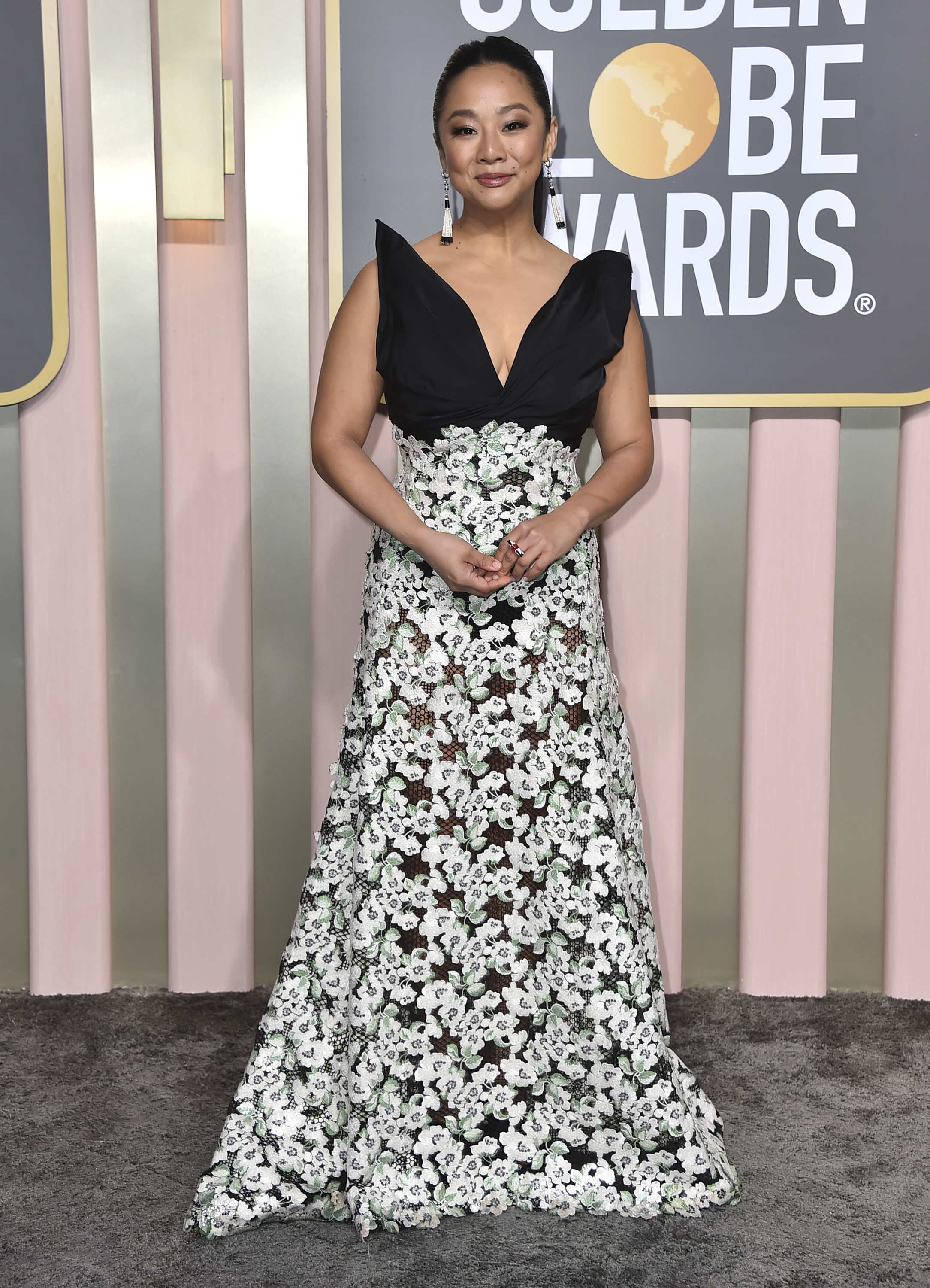 Stephanie Hsu wearing a gown with a black V-sleeve detail and a white and green floral skirt. 