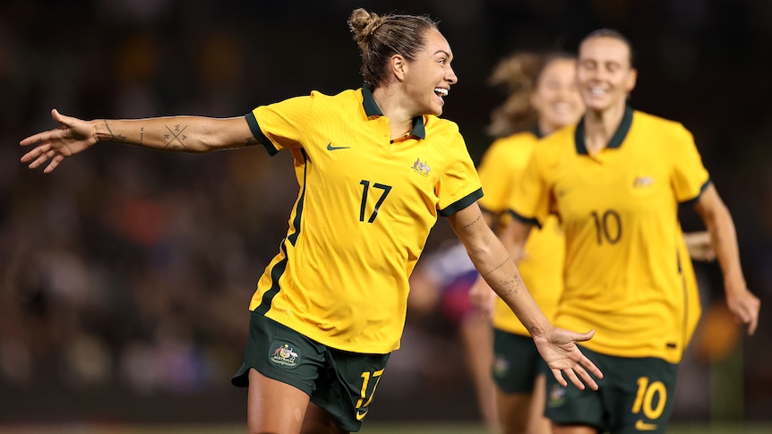 A Matildas player smiles as she celebrates scoring a goal against the USA.