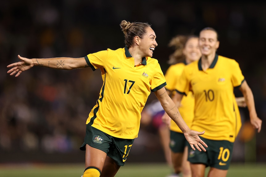 A Matildas player smiles as she celebrates scoring a goal against the USA.