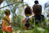 photo from behind two women and a child sitting in long grass