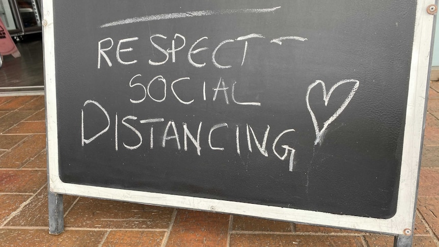 A blackboard sign outside a shop has the message - respect social distancing.