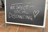 A blackboard sign outside a shop has the message - respect social distancing.