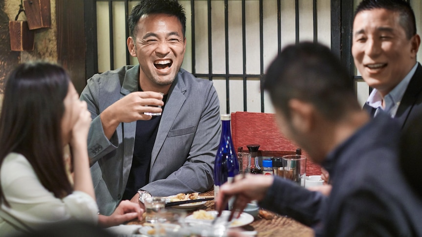 A group of Japanese friends share a laugh at a restaurant.