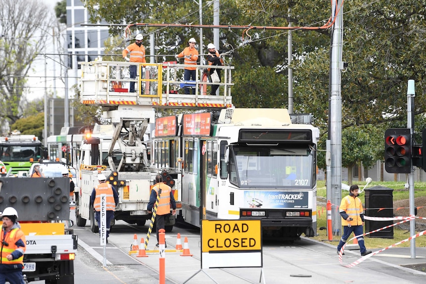 Workers on a mobile platform inspect the roof of a tram that earlier caught fire.