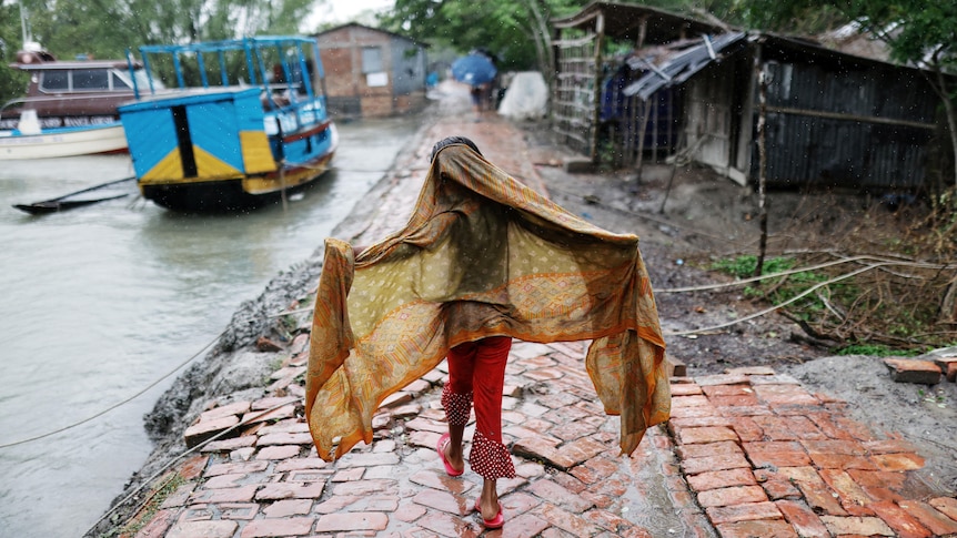 A young girl walks along a path before the Cyclone Remal hits the country in the Shyamnagar area of Satkhira, Bangladesh.