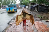 A young girl walks along a path before the Cyclone Remal hits the country in the Shyamnagar area of Satkhira, Bangladesh.