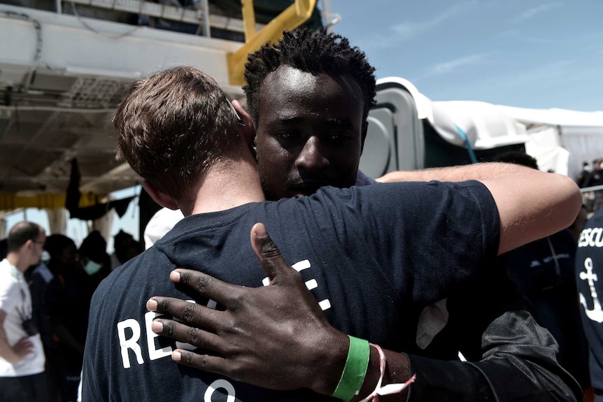A migrant hugs a crew member from the Aquarius rescue ship