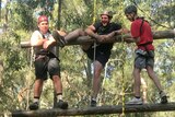 Two teenage boys and an uniformed police officer do a high ropes course.