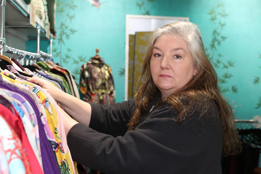 A woman searches through a clothing rack.