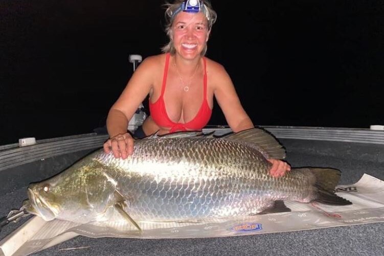 Woman smiles and holds a large fish.,