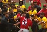 A baseball player fights a number of opponents in a massive fight on a baseball pitch as teammates rush in to help