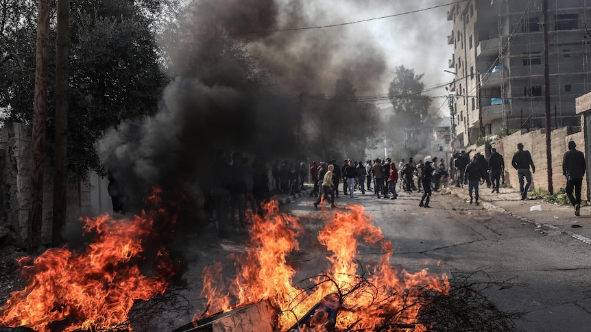 fire blazing and crowd gathering on the street in jenin