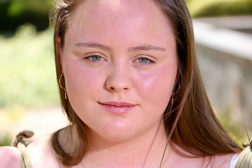 A close up of a young woman with hazel eyes.