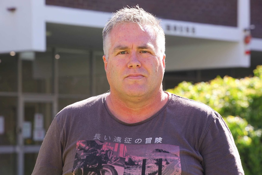 A mid shot of a man with short grey hair looking at the camera.