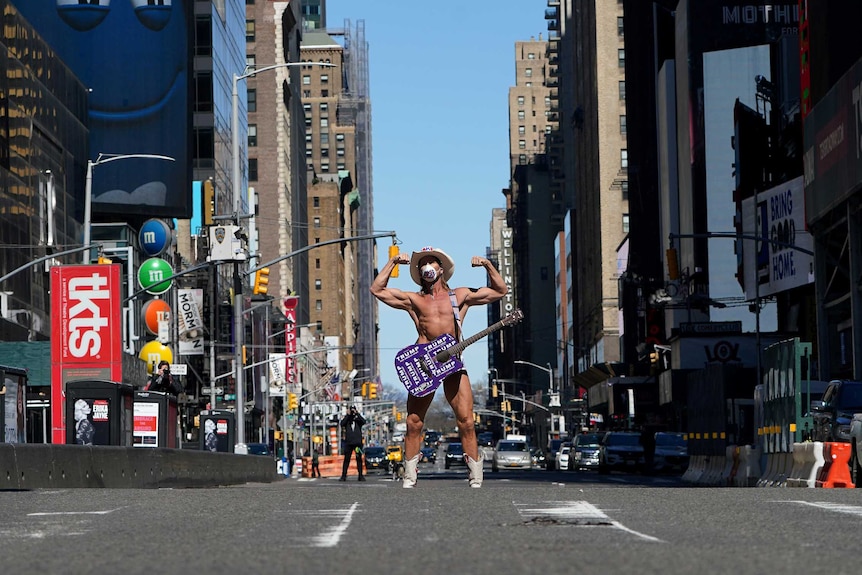 A man in his undies and a cowboy hat standing in Times Square alone