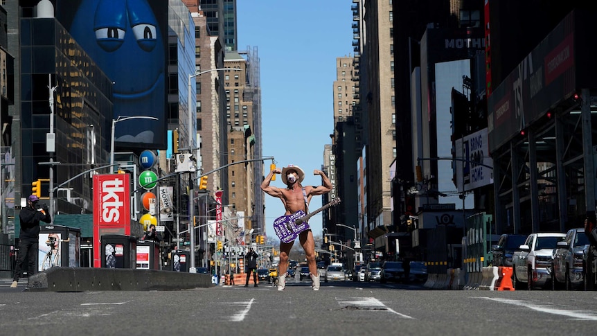 A man in his undies and a cowboy hat standing in Times Square alone