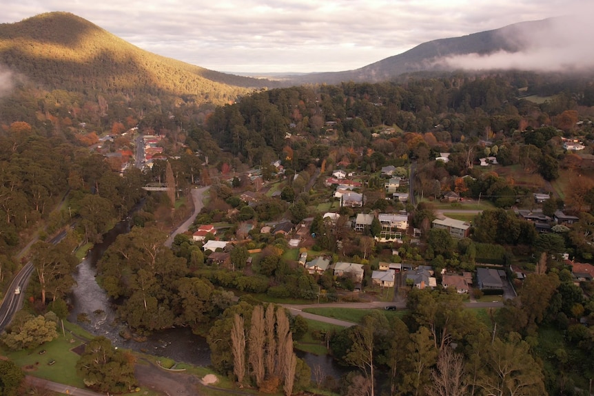A drone shot view of Warburton, showing houses, mountains and fog from afar. 