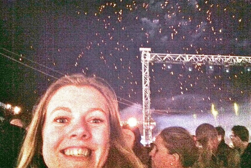 A selfie of a Daft Punk fan mixed in with the crowd as embers of fireworks dot the night sky